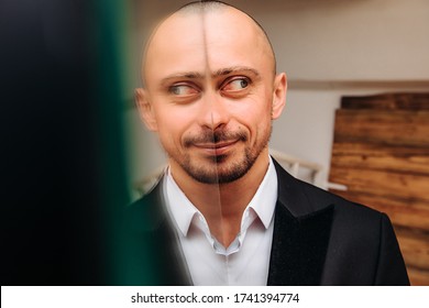 Crazy bald happy man grimace-stupid face. Funny and stupid guy in a suit, half of his face reflected in the mirror.