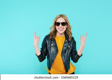 Crazy beautiful rock Girl in leather jacket and black sunglasses. Punk is not dead. Attractive cool young woman making horn sign hand gesture.