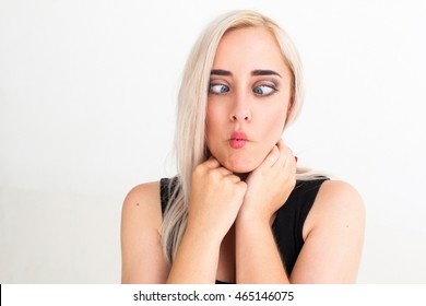 Crazy blonde woman makes squint for fun. Close-up portrait of cheerful funny blonde with strabismus, white background