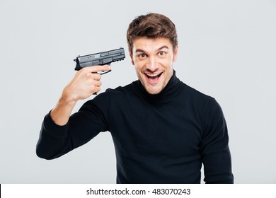 Crazy cheerful young man put gun to temple and laughing