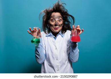 Crazy Chemist Holding Glass Flasks Filled With Toxic Chemical Compounds After Laboratory Explosion. Mad Wacky Lab Worker Having Beakers Filled With Liquid Substances After Failed Laboratory Experiment