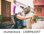 Crazy couple dancing and wearing dinosaur t-rex and unicorn mask - Senior elegant people having fun masked at carnival parade - Absurd, eccentric, surreal, fest and funny masquerade concept