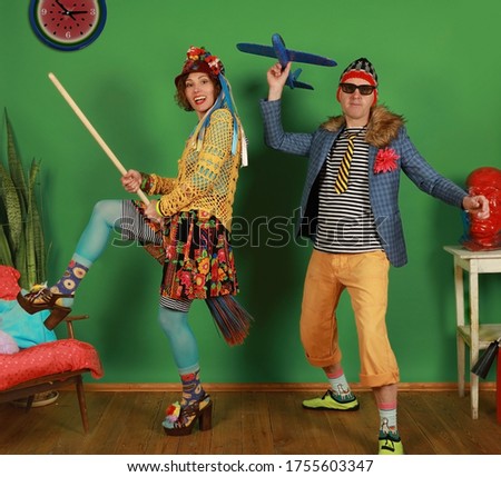 Crazy couple of freaks fool around in the studio in front of green background
