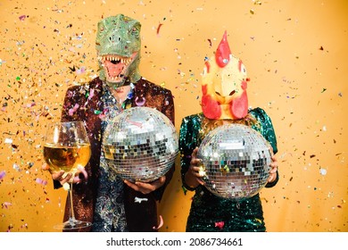 Crazy Couple Having Fun Holding Disco Balls And Champagne Glass At Party - Focus On Chicken Mask