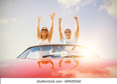 Crazy couple standing in red cabriolet on a sunny day - Powered by Shutterstock