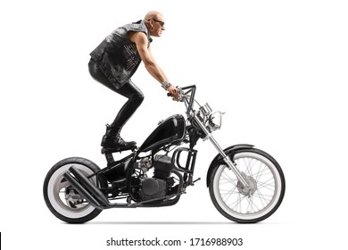 Crazy daredevil biker riding a chopper and standing on the seat isolated on white background