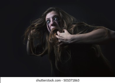 Crazy deranged woman pulling her hair out, scary and insane, halloween concept, possessed by evil spirits - Shutterstock ID 501071863