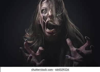 Crazy deranged woman pulling her hair out, scary and insane, halloween concept, possessed by evil spirits - Shutterstock ID 664329226