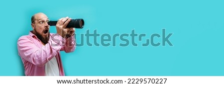 Crazy emotions. Young funny hipster tourist looking through a spyglass and considering the sights isolated on studio background. Looking for discounts, sale, seasonal sales. Colorful summer concept.