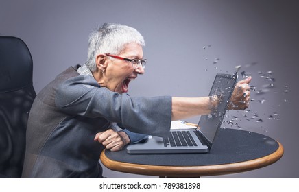 Crazy Enraged Senior Business Woman Punching Through Her Laptop, Frustrated Because It Doesn't Work Properly