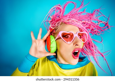 Crazy expressive trendy DJ girl in bright clothes, headphones and bright dreadlocks. Disco, party. Bright fashion.