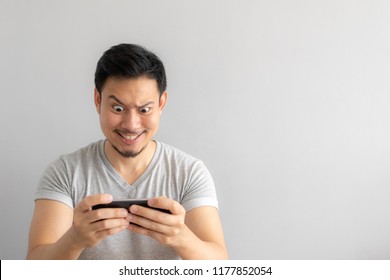 Crazy And Funny Face Of Asian Man Addicted To Play Mobile Game.