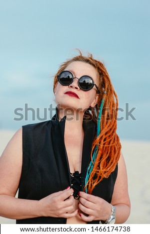 crazy funny grunge punk redhead woman with dreadlocks in office clothes and sunglasses in the desert 