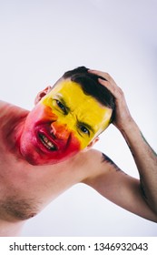 Crazy Guy Posing With A Painted Face. A Bizarre Portrait Of A Man With A Painted Body. Concept: Sports Fan