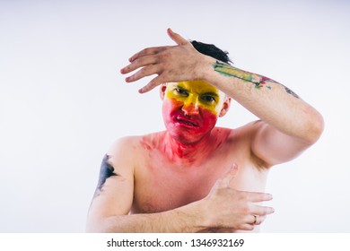Crazy guy posing with a painted face. A bizarre portrait of a man with a painted body. Concept: sports fan