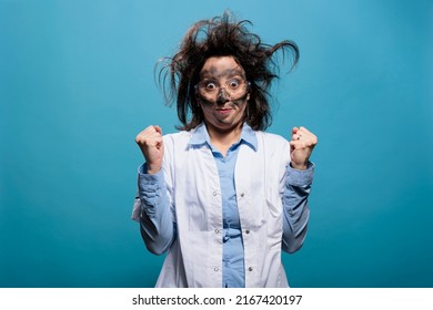 Crazy Infuriated Chemist With Messy Hair And Face, Clenching Fists In Anger While Being Upset For Failed Scientific Experiment. Irritated Wacky Scientist With Awful Hairstyle And Dirty Face.