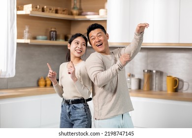 Crazy Japanese Couple Having Fun While Cooking Together At Weekend At Kitchen, Positive Asian Middle Aged Man And Young Woman Standing Back To Back, Singing And Dancing, Copy Space