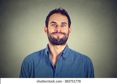 Crazy looking man making funny faces isolated on gray wall background 
