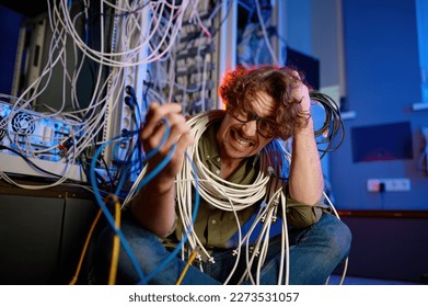 Crazy mad computer engineer wrapped in wires and cables in server room - Powered by Shutterstock