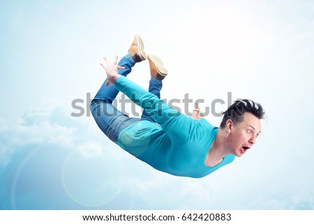 Crazy man in blue shirt and jeans is flying in the sky. Jumper concept