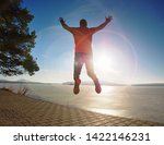 Crazy man jumping while joogging at morning spring lake bay. Sunny morning with clear blue sky above.
