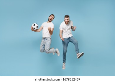 Crazy men guys friends in white t-shirt isolated on pastel blue background. Sport leisure lifestyle concept. Cheer up support favorite team with soccer ball, jumping, doing winner gesture, screaming - Shutterstock ID 1679652457