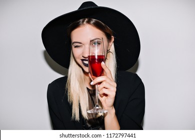 Crazy party time of beautiful woman in elegant black hat with a glass of champagne celebrating new year, birthday, halloween, having fun, dancing,drinking alcohol cocktails.Emotion face, smile