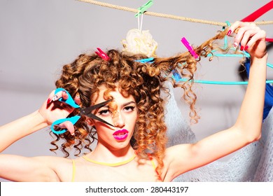 Crazy Playful Young Beautiful Fashionable Woman With Curly Hair Holding Scissors Cutting Curle Looking Forward Indoor On Grey Wall Background Copyspace, Horizontal Picture