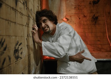 Crazy prisoner or psychiatric hospital patient scratching wall with nails