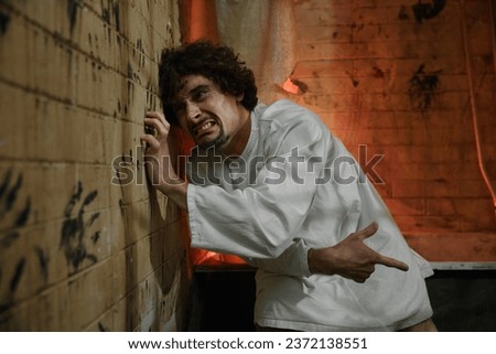 Crazy prisoner or psychiatric hospital patient scratching wall with nails