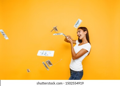 Crazy rich woman throws away money banknotes, lots of dollars isolated on yellow background