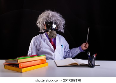 Crazy Science Teacher In White Coat With Unkempt Hair Sitting At The Desk  Wears A Gas Mask  