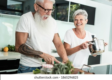 Crazy senior couple cooking together at home - Joyful elderly lifestyle and food nutrition concept - Main focus on woman face