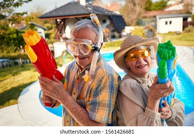 Crazy Senior Happy People Have Fun On Vacation Playing With  Water Gun