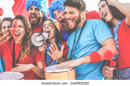 Crazy Sport Fans Playing Drums And Screaming While Supporting Their Team - Football Supporters Having Fun Inside Stadium For Soccer Match - Event Concept - Focus On Right Man Face