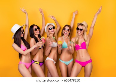 Crazy Swimpool Hen Party! Dance And Go Insane! Five Cute Ladies Are Posing On Bright Yellow Background In Swimming Suits And Sunglasses, Caps, With Raised Up Hands, Having Wine And Champagne, Martini