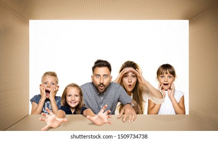 Crazy Things. Shocked And Astonished People Opening The Biggest Postal Package. Excited Family On Top Of Cardboard Box Looking Inside. Gift, Present, Delivery, Shipment, Sales, Black Friday Concept.