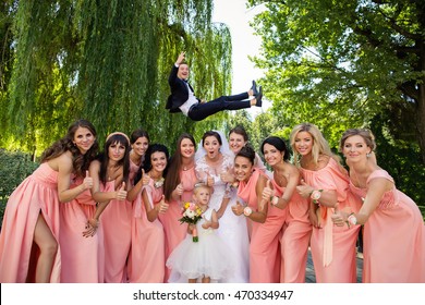 Crazy Wedding. Bride And Bridesmaids Having Fun After Wedding Ceremony. Groom Flying In Background With Help Of Groomsmen. Bridesmaid Dresses. Bride Groom And Guests At Wedding Day. Wedding Concept