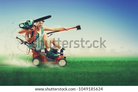 Crazy workman covered with instruments driving lawn mower over green grass
