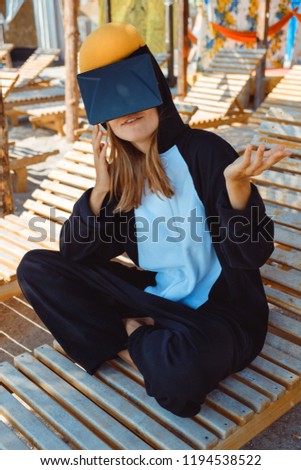 Crazy young beautiful skinny woman in penguin costume with VR glasses on the summer beach