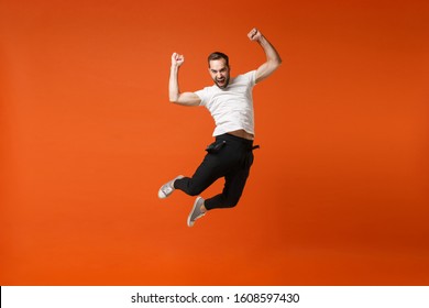 Crazy young man in casual white t-shirt posing isolated on orange background in studio. People lifestyle concept. Mock up copy space. Having fun, fooling around, jumping, clenching fists like winner - Shutterstock ID 1608597430