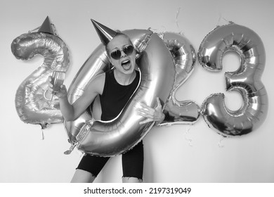 Crazy Young Woman Making Funny Face. Lonely Girl Celebrating New Year 2023 At Home. Silvester Party. December 31. January 1. Big Number Balloons. Lady Posing In Hole Of Zero Shaped Balloon.