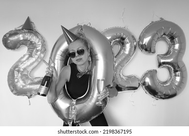 crazy young woman making funny face. lonely girl celebrating new year 2023 at home. silvester party. december 31. january 1. big number balloons. lady posing in hole of zero shaped balloon.