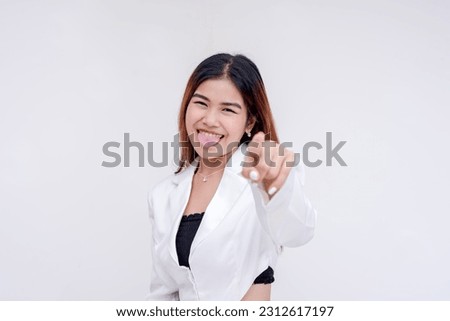 A crazy young woman pointing at the camera with her tongue sticking out. Taunting or teasing a friend. Isolated on a white background.