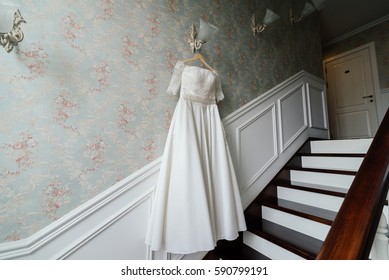 Cream bride hang on the lamp against the wall next to the stairs in the hotel - Powered by Shutterstock