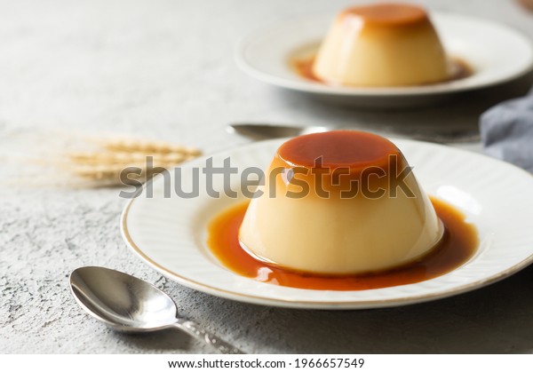 Cream caramel pudding with caramel sauce in plate\
on white rustic table