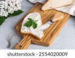 Cream cheese with herbs and seasoning on slice of fresh crunchy rye bread with cheese knife nearby