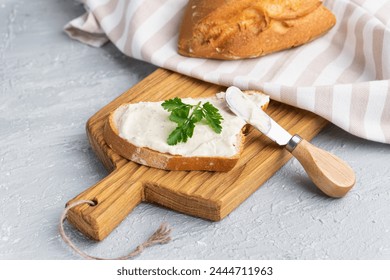 Cream cheese with herbs and seasoning on slice of fresh crunchy rye bread with cheese knife nearby - Powered by Shutterstock