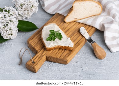 Cream cheese with herbs and seasoning on slice of fresh crunchy rye bread with cheese knife nearby - Powered by Shutterstock