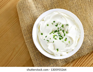 Cream Cheese, Quark Or Yogurt In A White Bowl. Dairy Product With Fresh Herbs, Healthy Eating Theme. Wooden Table Background.